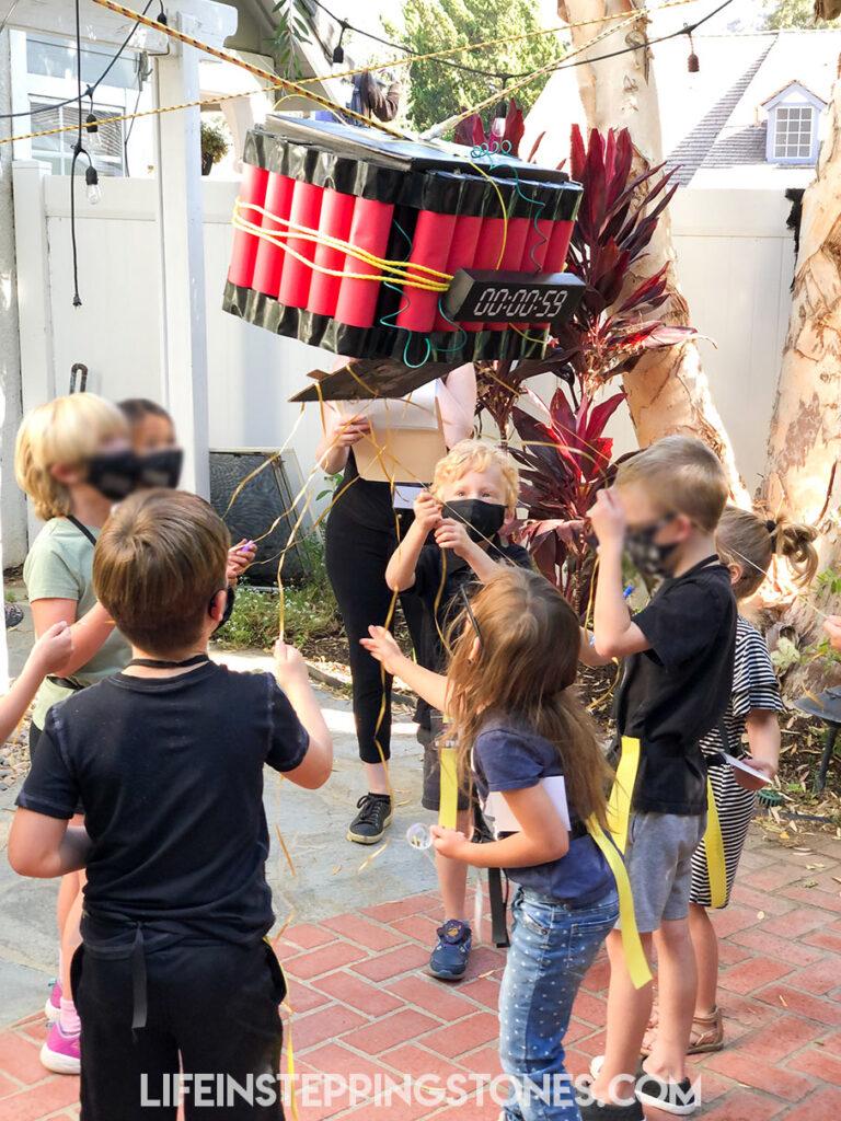 Spy Party Activities: Kid spies defuse the pull string time bomb piñata at Secret Agent birthday party.